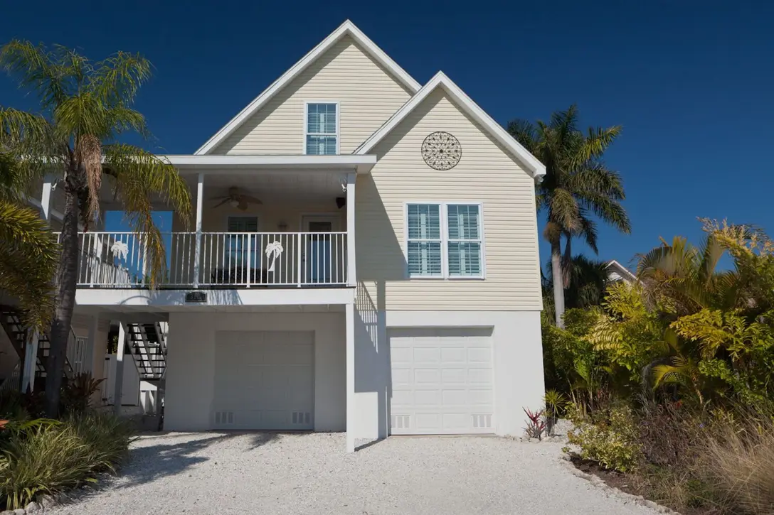 Happy Island Cottage front exterior: two-story coastal home with palms, Holmes Beach