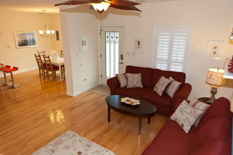 Living room with two red sofas and the dining area beyond, Happy Island Cottage